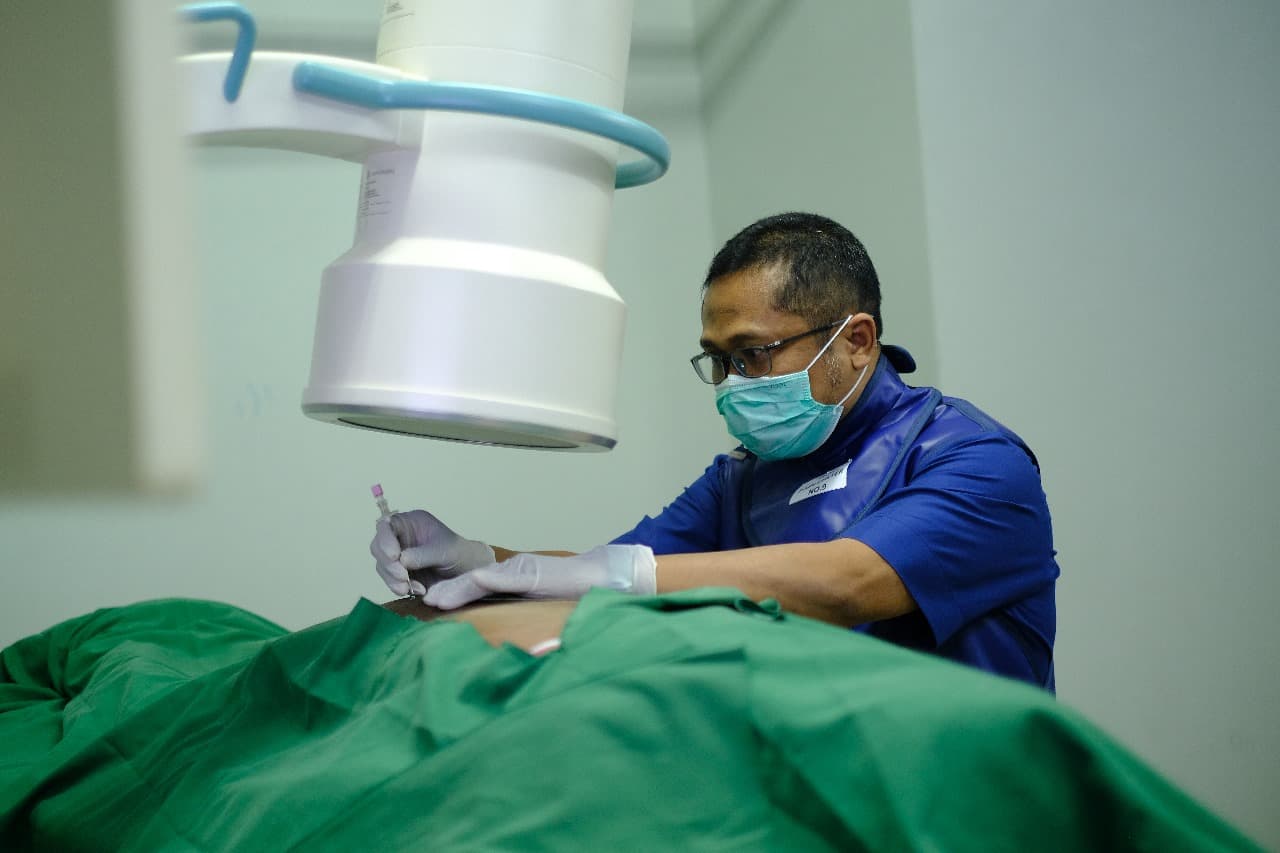 Doctor performing fluoroscopy-guided pain intervention procedure